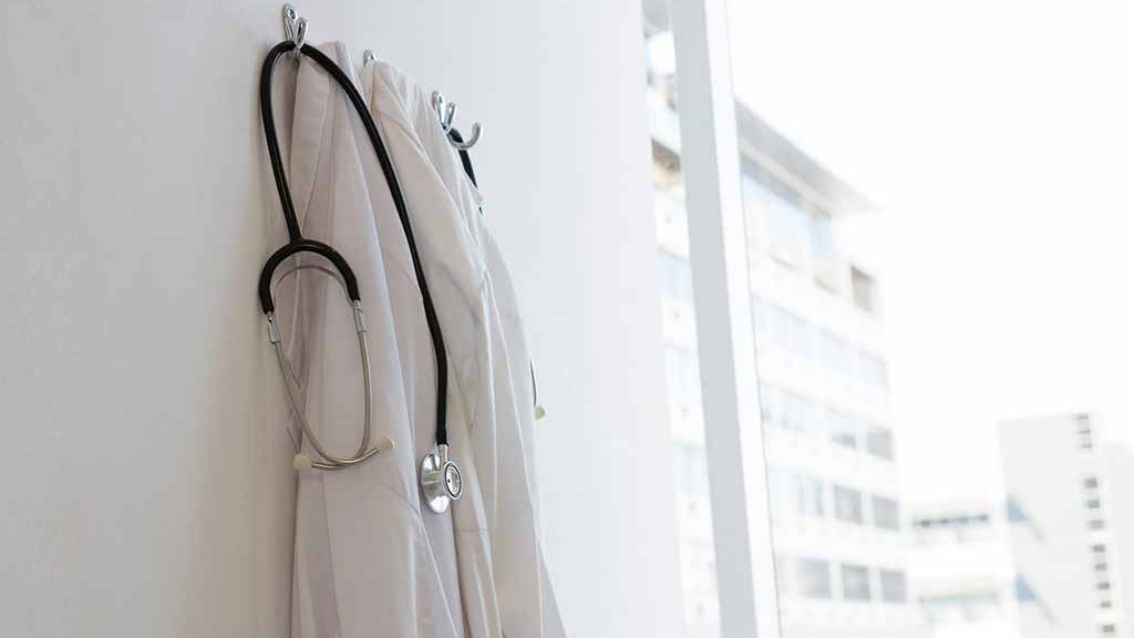 Blouse de soignant suspendue à un crochet symbolisant la suspension des soignants refusant de se faire vacciner